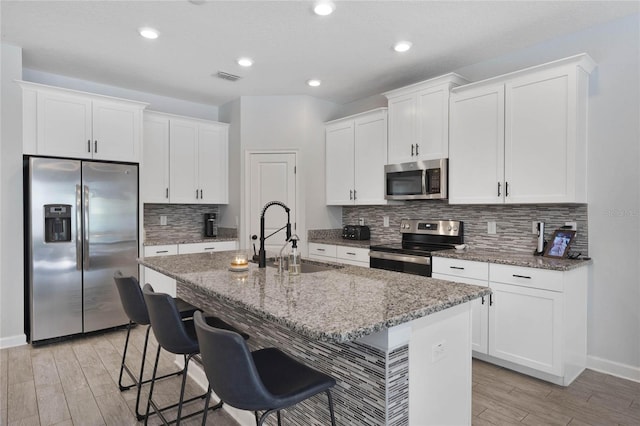 kitchen with visible vents, a sink, appliances with stainless steel finishes, light wood-style floors, and a kitchen island with sink