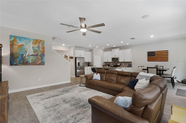 living area featuring recessed lighting, baseboards, light wood-style flooring, and ceiling fan