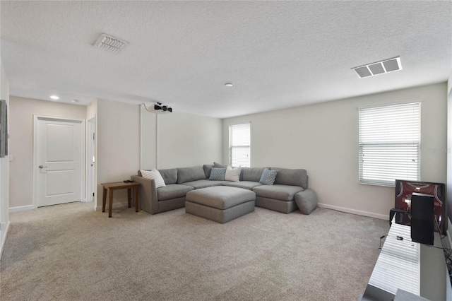 living area with carpet, visible vents, and a textured ceiling