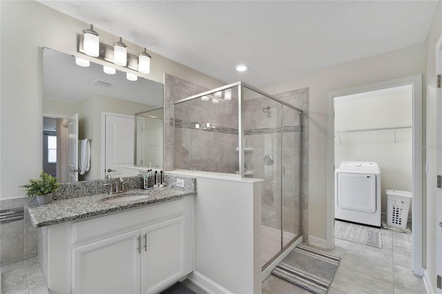 bathroom featuring vanity, washer / dryer, a shower stall, a spacious closet, and tile patterned floors