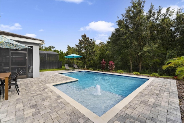 pool with glass enclosure, a patio, and fence