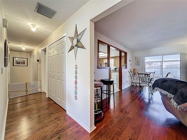 hallway with wood finished floors, baseboards, and a textured ceiling