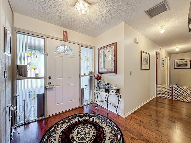 entrance foyer with a textured ceiling, baseboards, and wood finished floors