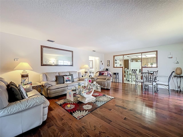 living room with wood finished floors, visible vents, and a textured ceiling