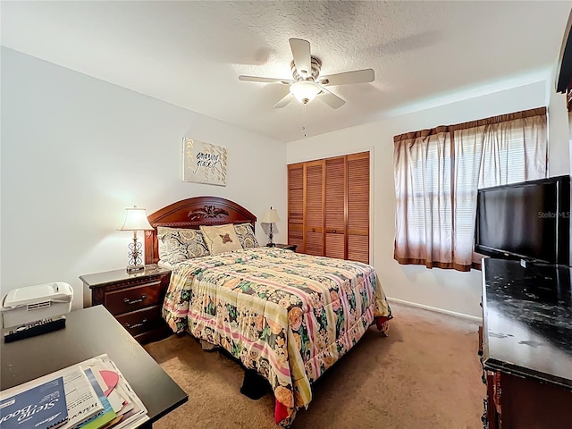 bedroom with baseboards, carpet floors, ceiling fan, a closet, and a textured ceiling