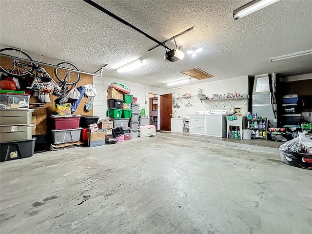 garage featuring concrete block wall, a garage door opener, and separate washer and dryer