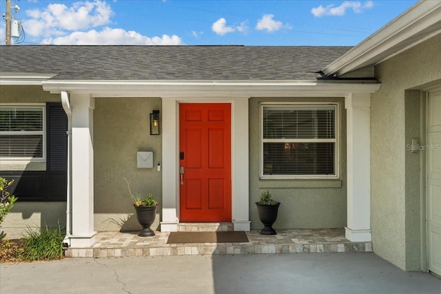 doorway to property with covered porch and stucco siding