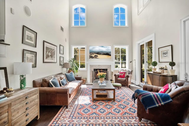 living room with visible vents, dark wood-type flooring, a towering ceiling, and a fireplace