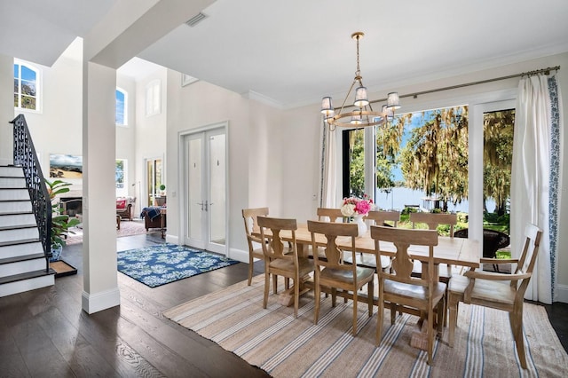 dining space with dark wood-type flooring, crown molding, stairs, french doors, and an inviting chandelier