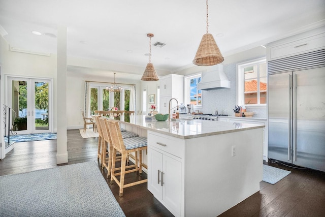 kitchen featuring visible vents, premium range hood, dark wood finished floors, stainless steel built in fridge, and white cabinets