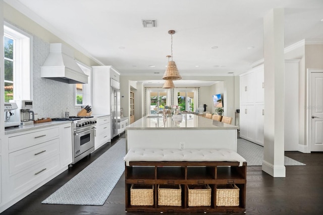 kitchen with visible vents, high quality appliances, light countertops, custom range hood, and white cabinets