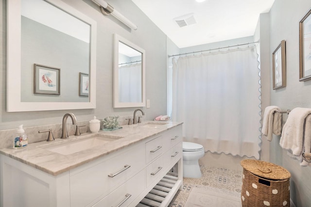 bathroom featuring tile patterned floors, double vanity, toilet, and a sink