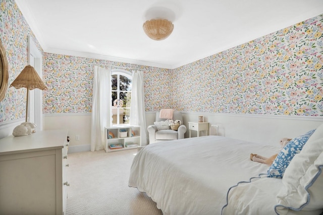 bedroom featuring wallpapered walls, ornamental molding, a wainscoted wall, and light carpet