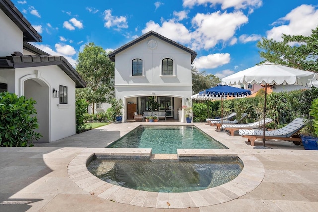 back of house with an outdoor living space, stucco siding, a patio, and a pool with connected hot tub