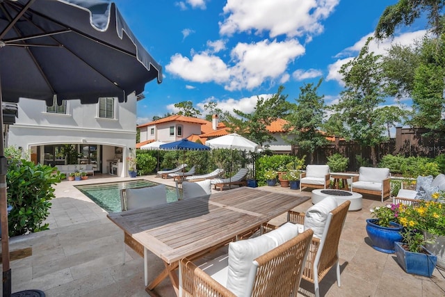 view of pool featuring outdoor dining space, fence, an outdoor living space with a fire pit, a fenced in pool, and a patio area