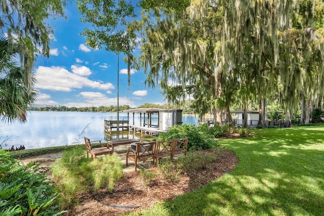 view of dock with a lawn and a water view