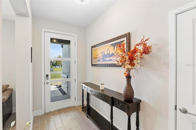 doorway to outside with baseboards and light wood finished floors