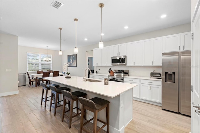 kitchen featuring visible vents, a sink, a kitchen breakfast bar, light wood-style floors, and appliances with stainless steel finishes