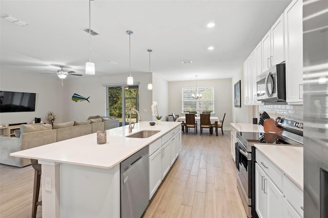 kitchen featuring visible vents, a sink, stainless steel appliances, light countertops, and backsplash