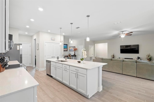 kitchen with white cabinetry, light wood-style floors, stainless steel appliances, and a sink