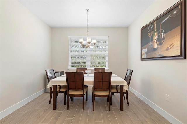 dining area featuring an inviting chandelier, baseboards, and light wood-style floors