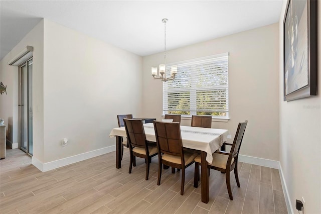 dining area with baseboards, a chandelier, and wood finish floors