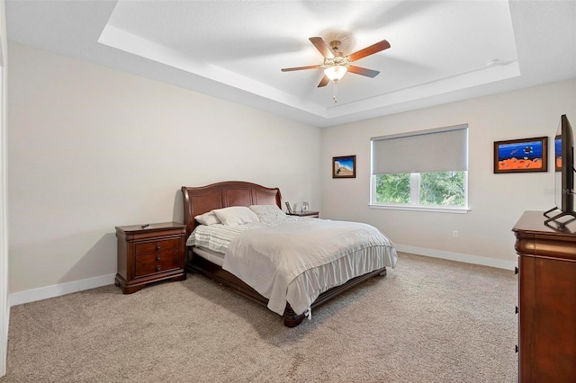 bedroom with a tray ceiling, baseboards, light carpet, and ceiling fan