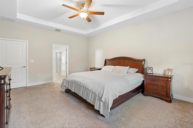 bedroom featuring a raised ceiling, light colored carpet, visible vents, and baseboards