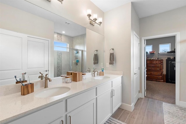 bathroom with a sink, a spacious closet, a stall shower, and double vanity