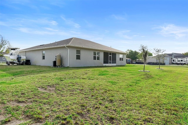 back of property featuring a lawn and stucco siding