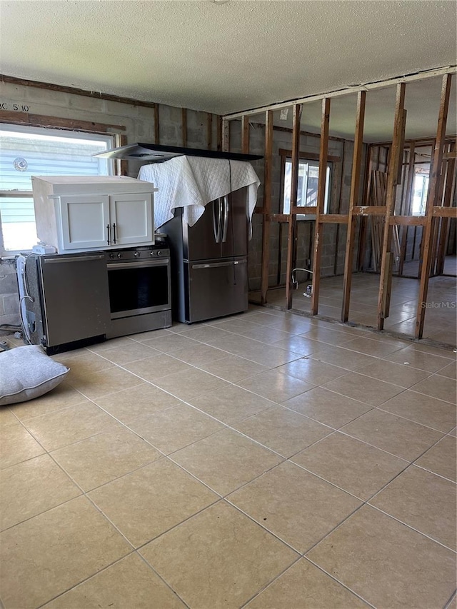 kitchen featuring light tile patterned floors, a healthy amount of sunlight, freestanding refrigerator, and oven