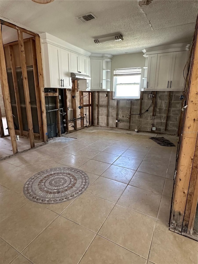 interior space featuring light tile patterned floors, visible vents, and a textured ceiling