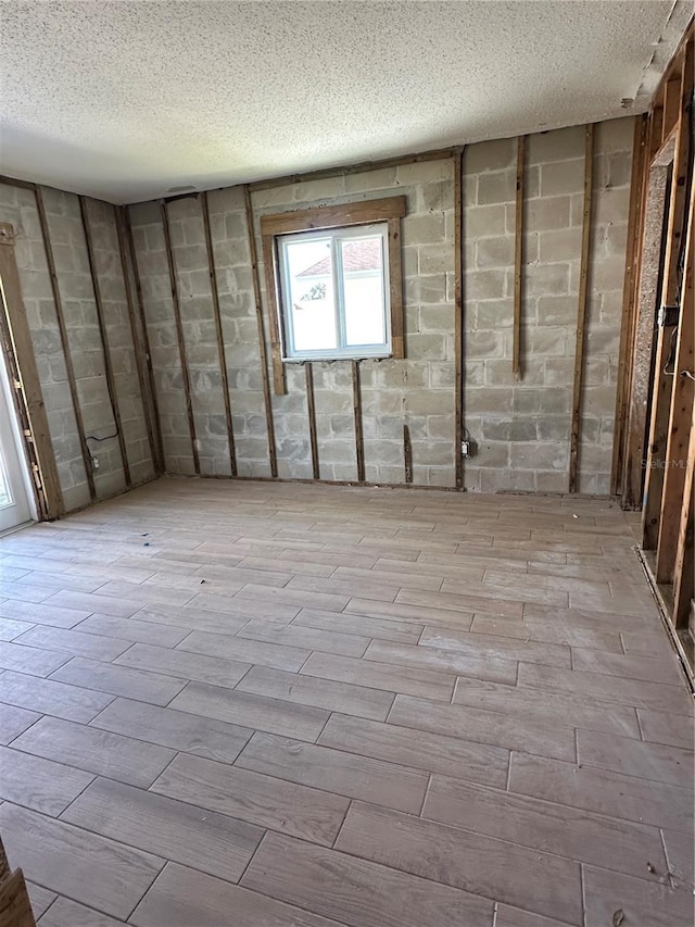 empty room with concrete block wall, a textured ceiling, and wood tiled floor