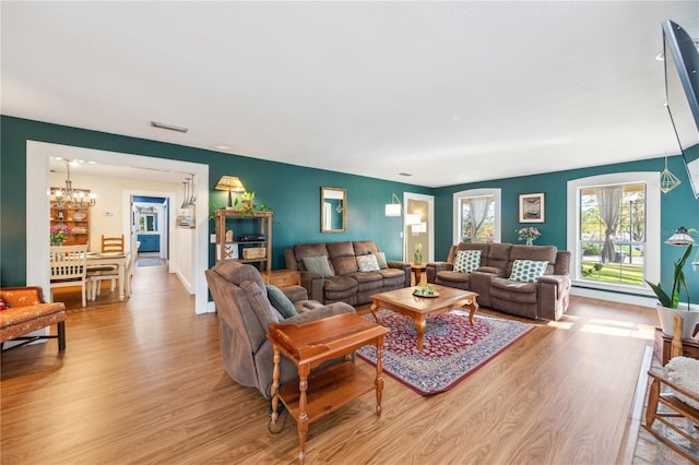 living area with a notable chandelier, light wood-style floors, and visible vents