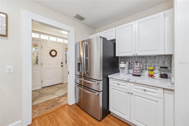 kitchen with light countertops, white cabinets, stainless steel fridge with ice dispenser, and light wood-type flooring