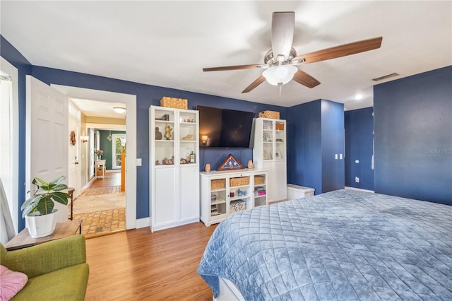 bedroom with wood finished floors, visible vents, and ceiling fan