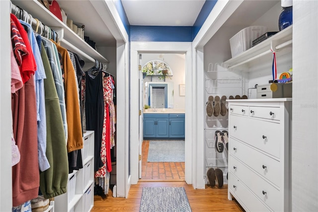 walk in closet with a sink and light wood finished floors