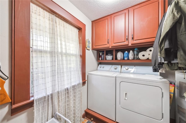 laundry area featuring water heater, cabinet space, washer and dryer, and a textured ceiling