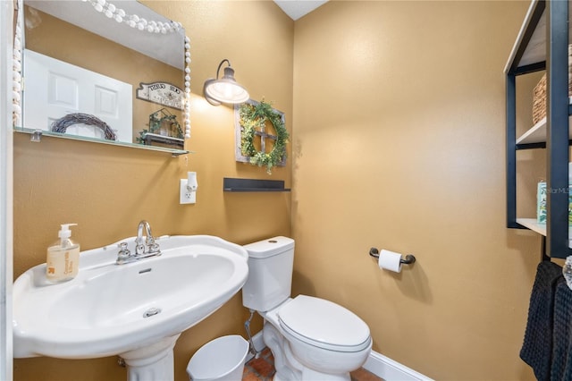 bathroom featuring toilet, baseboards, and a sink