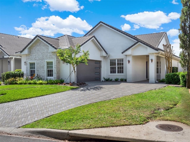 modern farmhouse style home featuring stucco siding, driveway, a front yard, a garage, and a tiled roof