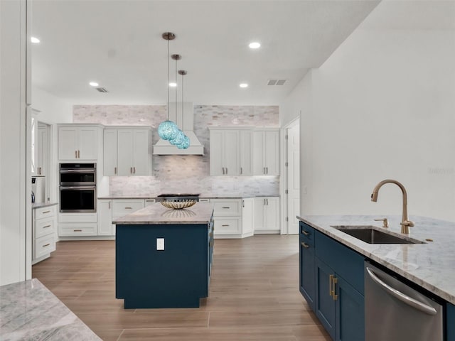 kitchen with a sink, blue cabinetry, white cabinetry, and stainless steel appliances