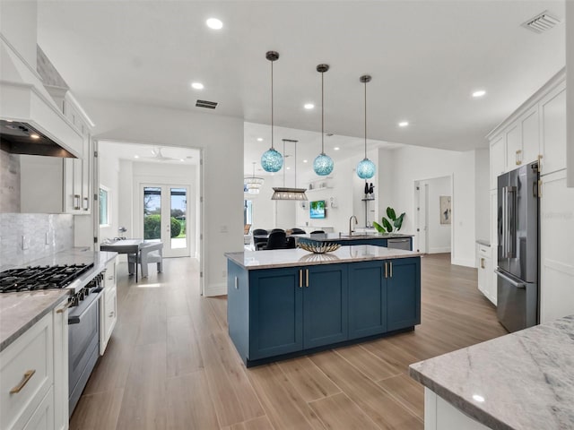 kitchen with visible vents, premium range hood, premium appliances, white cabinetry, and blue cabinets