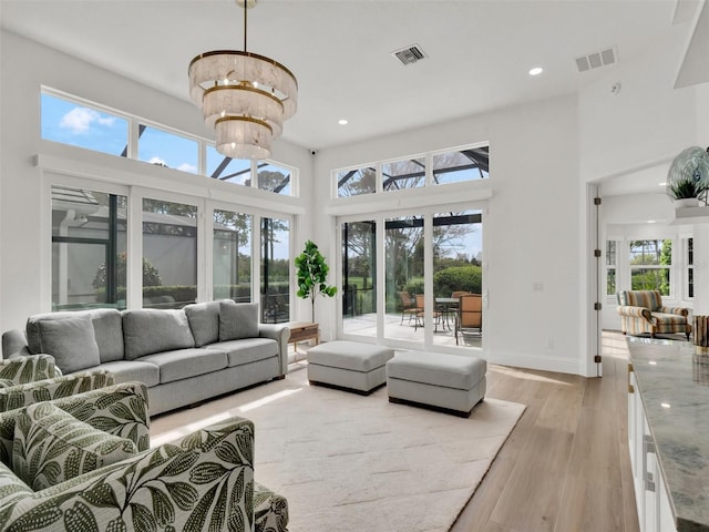 living room with light wood finished floors, visible vents, baseboards, recessed lighting, and a high ceiling