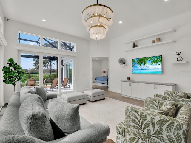 living area featuring recessed lighting, light wood-style floors, an inviting chandelier, and a towering ceiling