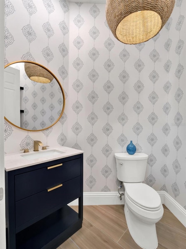 bathroom with baseboards, toilet, wood finished floors, and vanity