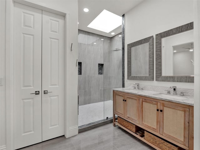 full bath featuring double vanity, a stall shower, a skylight, and a sink