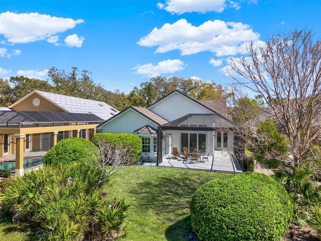 rear view of house with stucco siding, a patio, and a lawn