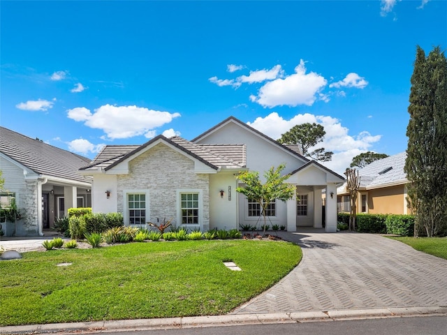 view of front facade featuring stucco siding, a tile roof, and a front yard