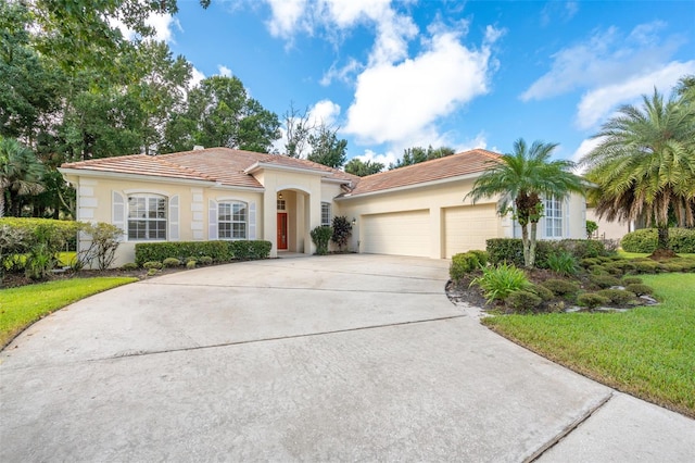 mediterranean / spanish-style house with stucco siding, a garage, driveway, and a tile roof