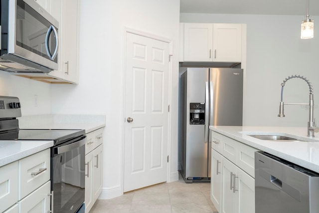 kitchen with a sink, light countertops, white cabinets, appliances with stainless steel finishes, and pendant lighting